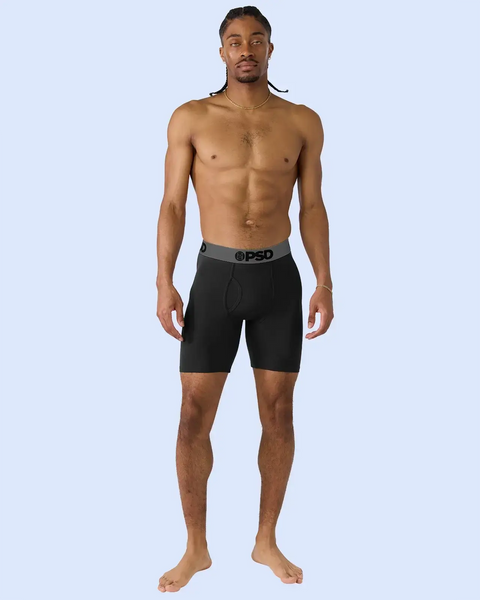 Man wearing black boxer briefs with grey waistband against light blue background.